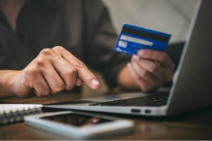 manos tecleando en laptop y tarjta de credito