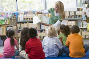 Niños de diversas nacionalidades escuchando a una maestra leer en una clase de jardín infantil en Alemania.
