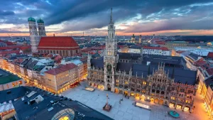 Vista aérea del centro de Múnich al atardecer con edificios históricos iluminados.