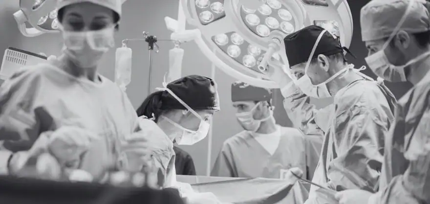 Médicos cirujanos realizando una cirugía, representando la comparación entre ejercer como médico en Colombia y Alemania.