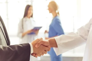 Médico y representante saludando tras firma de contrato en Alemania
