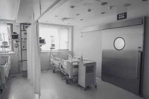 Sala hospitalaria vacía con camas y monitores médicos, representando la escasez de médicos en el mundo.