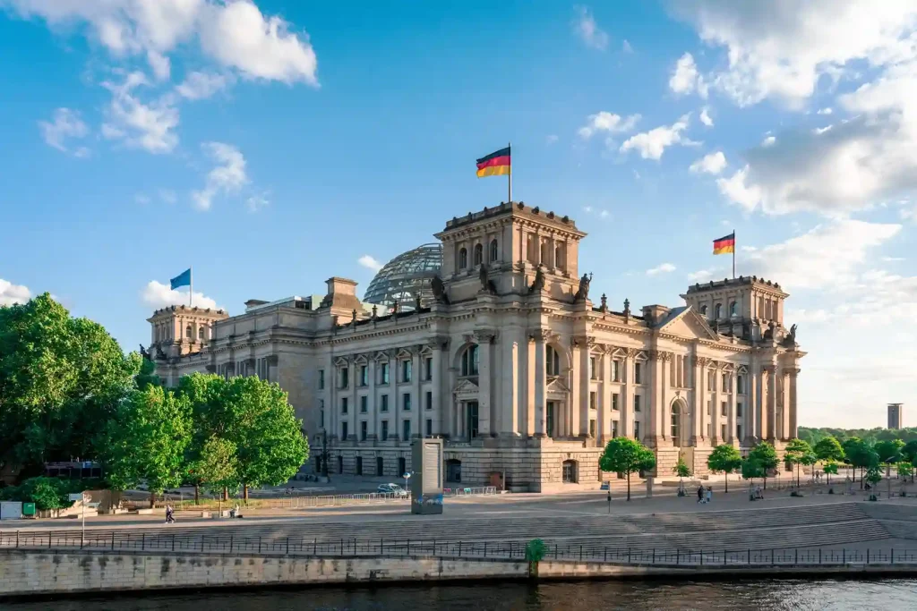 Edificio institucional en Alemania con bandera alemana, representando el respaldo legal y el liderazgo de NOMII en el acompañamiento a médicos latinoamericanos y la homologación de títulos médicos
