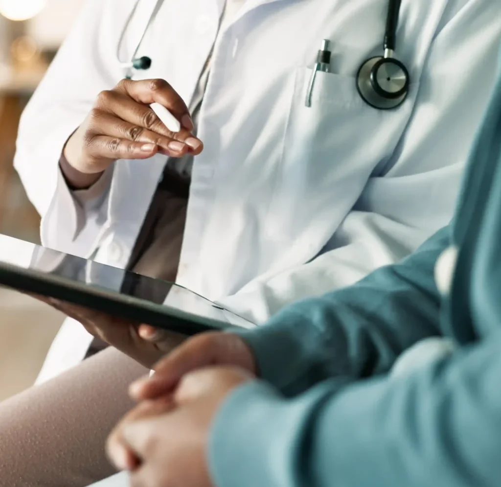 Médico revisando documentación clínica con una tablet durante una consulta, representando el acompañamiento profesional del Programa ZAI para la homologación y la integración hospitalaria en Alemania